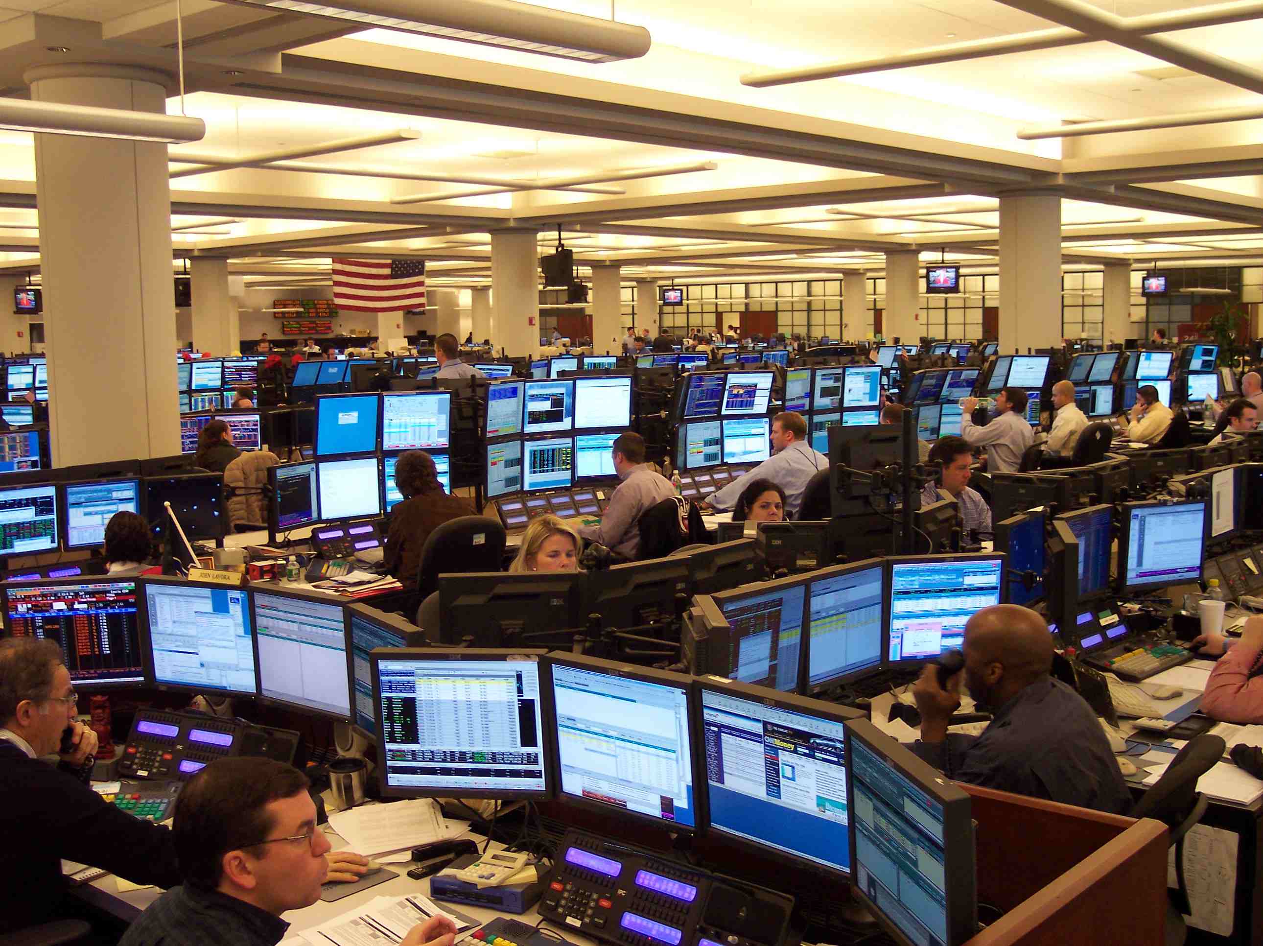 Traders at a desk in front of market data screens